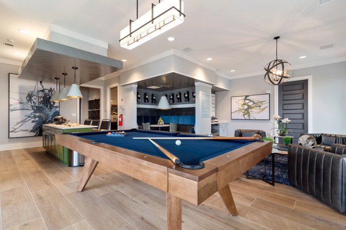 A clubhouse equipped with a pool table, a well-appointed community kitchen, and multiple cozy seating areas.