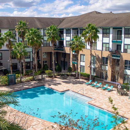 Captivating aerial vista showcasing the swimming pool and sun-drenched sundeck, adorned with inviting lounge chairs amidst the apartment enclave at Millenia 700.