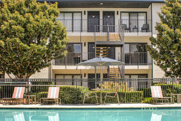 The exterior of the apartments at Vue at Knoll Trail with the sparkling pool in front of them. 