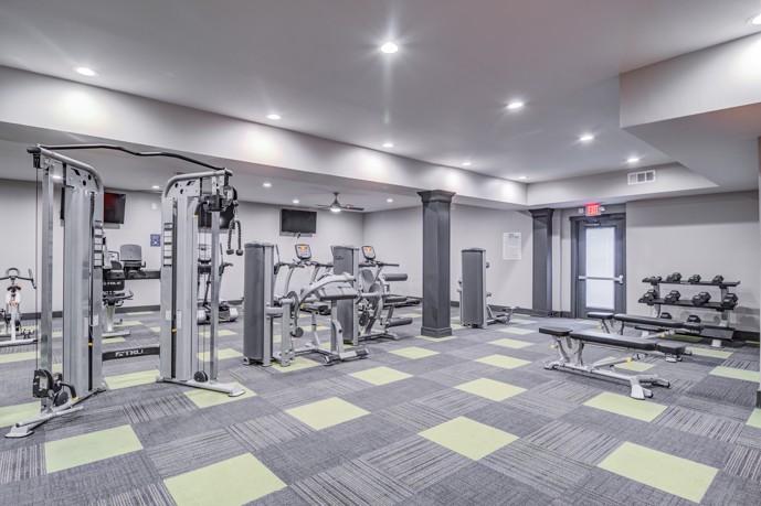 A gym room with exercise equipment and mirrors, perfect for working out and staying fit.