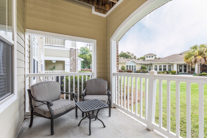 Patio view of the St James at Goose Creek apartment community with 2 chairs and a small table.