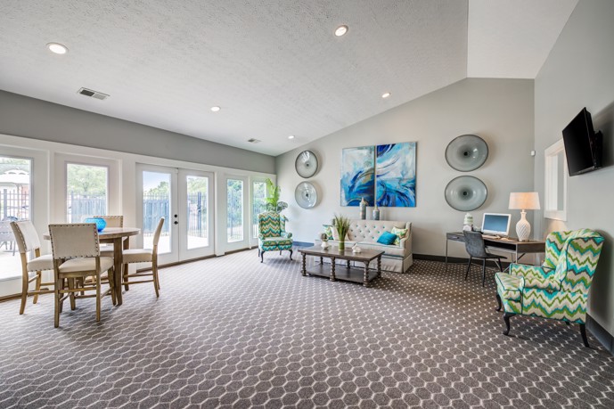 Relax in style at The Commons at Canal Winchester clubhouse, featuring cozy carpeting, comfortable lounge seating, and an expanse of glass doors that let in plenty of natural light.