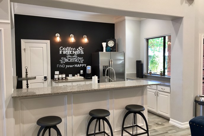 The clubhouse lounge at The Delano at North Richland Hills adorned with a kitchen bar, providing a welcoming space for residents to gather.