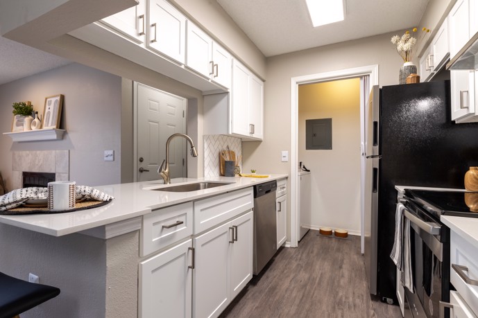 The Augusta apartments, stylish kitchen, boasting white shaker cabinets, sleek stainless steel appliances, and the added convenience of an adjacent laundry room.