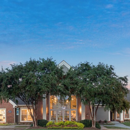 The exterior of the leasing office at The Village at Auburn, featuring two large trees in front, providing a welcoming and natural ambiance to visitors and residents.