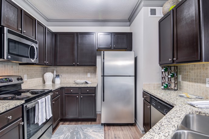 A large kitchen with dark brown cabinets, stainless steel appliances, and granite countertops at Waterstone at Big Creek.