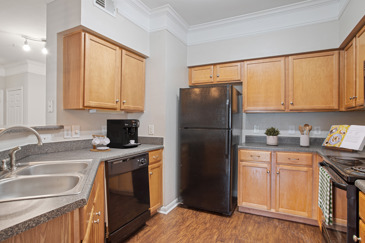Classic apartment kitchen with wooden cabinets, black appliances, and a grey countertop