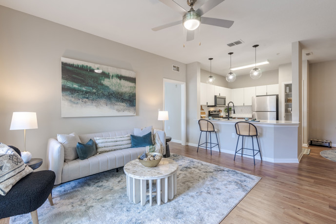 A spacious open-floor plan encompassing the living room, dining room, and kitchen, tastefully furnished and adorned with modern décor at The Enclave at Tranquility Lake, in Riverview, FL.