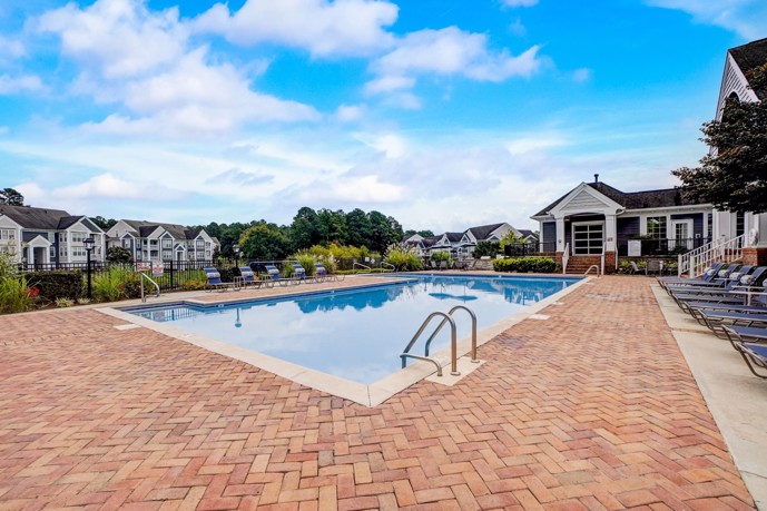 The stunning pool at The Village at Auburn in Durham, NC, surrounded by comfortable loungers, providing a perfect spot for residents to relax and enjoy a refreshing swim in a luxurious and serene setting.