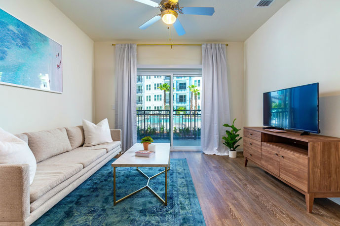 Inviting living space featuring a ceiling fan, wood-style flooring, and expansive windows, epitomizing the comfortable ambiance.