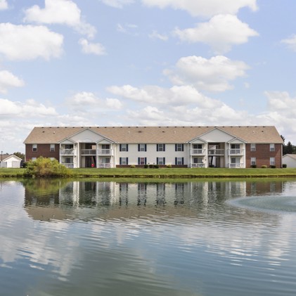 Distant view of the exterior of Collier Park apartments in Columbus, OH situated across from a large pond