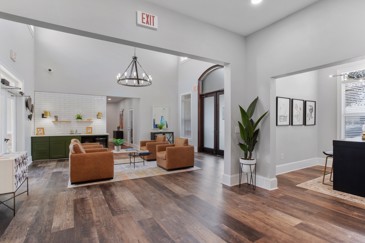 Open and spacious community clubhouse with grey walls, large plant, modern chandelier, and lots of light