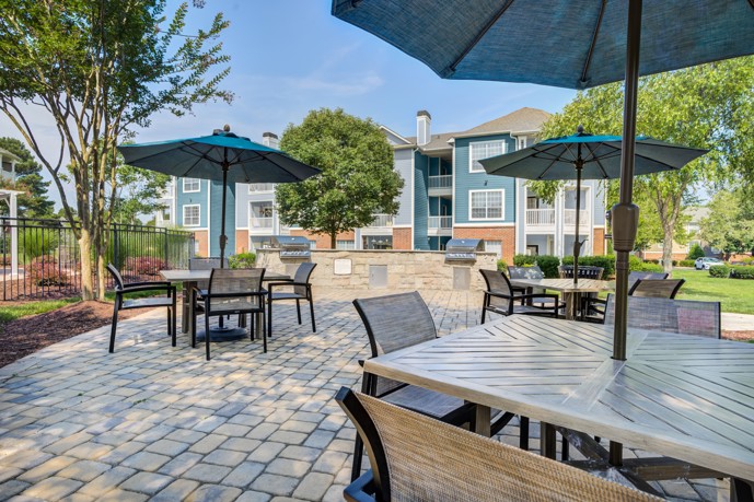 An inviting outdoor sitting area at Thornhill apartments, featuring shaded umbrellas and tables, providing a relaxing space for residents to enjoy the fresh air and socialize.