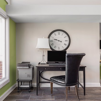 Apartment clubhouse workstation with a chair and desk with a computer and large round wall clock