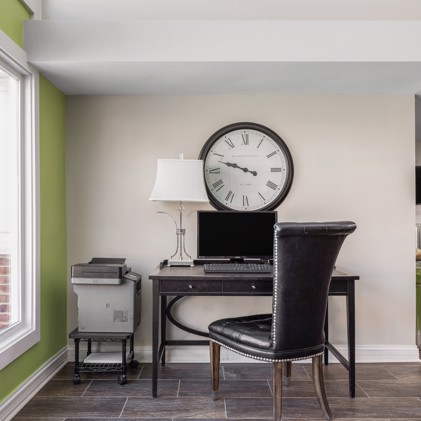 Apartment clubhouse workstation with a chair and desk with a computer and large round wall clock