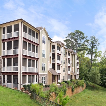 Exterior corner view of Aston apartments in Wake Forest, NC, with the building sitting on top of a hill on a sunny day