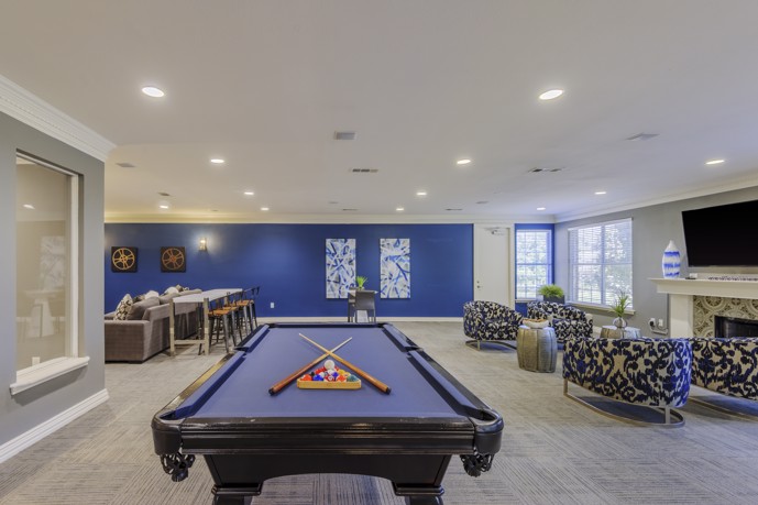 Community room within the clubhouse, featuring a billiards table, a cozy fireplace lounge, and comfortable seating area.