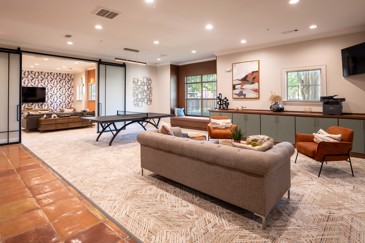 The clubhouse game room with a ping pong table, couches and a room for watching TV at The Pointe at Vista Ridge.
