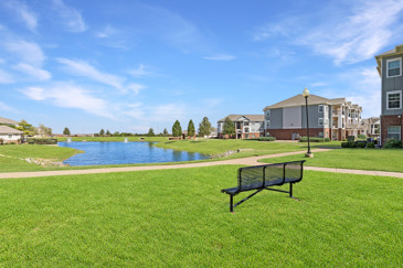 Exterior view of The Shores apartments in Oklahoma City, OK, showcasing modern architecture, landscaped grounds, and a large pond.