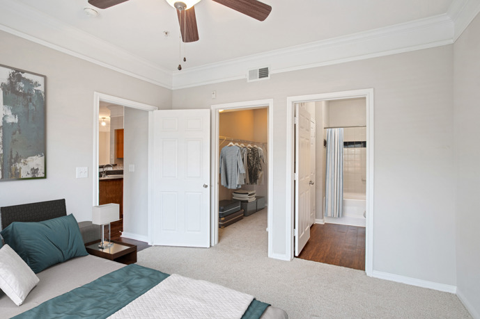 Carpeted apartment with three open doors, one to the closet, one to the bathroom, and one to the bathroom