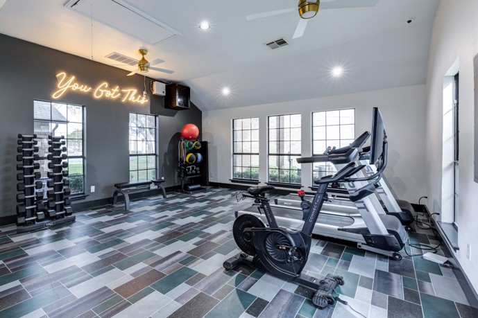 Fitness center featuring several windows, ceiling fans, and a variety of cardio and weight equipment.