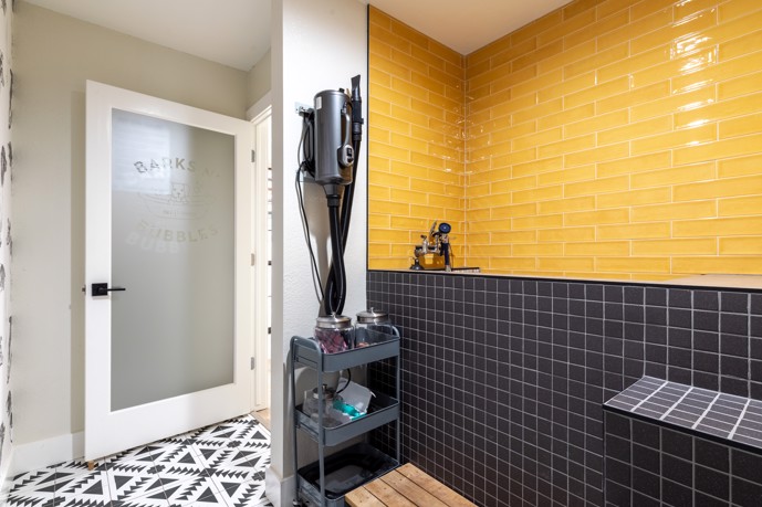 A contemporary tiled pet spa equipped with a bathtub and essential cleaning supplies, providing a modern amenity for pet owners at The Augusta in Oklahoma City, Oklahoma.
