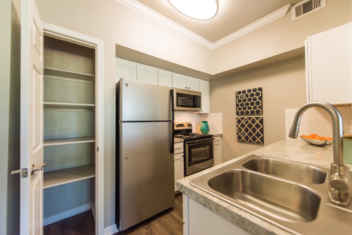 Kitchen equipped with a spacious pantry, stainless steel appliances, and a double-basin sink.