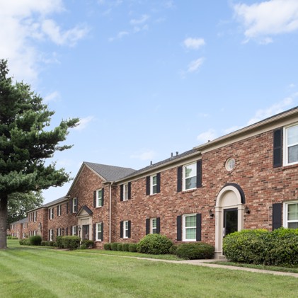 Two-story brick apartment building exterior, set against lush grass, within the Jamestown at St. Matthews community.