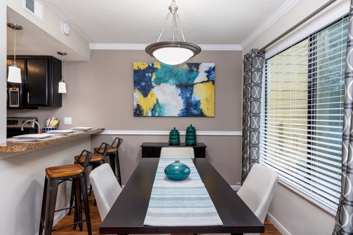 A dining room, boasting a large window, adjacent to a convenient breakfast bar and well-appointed kitchen.