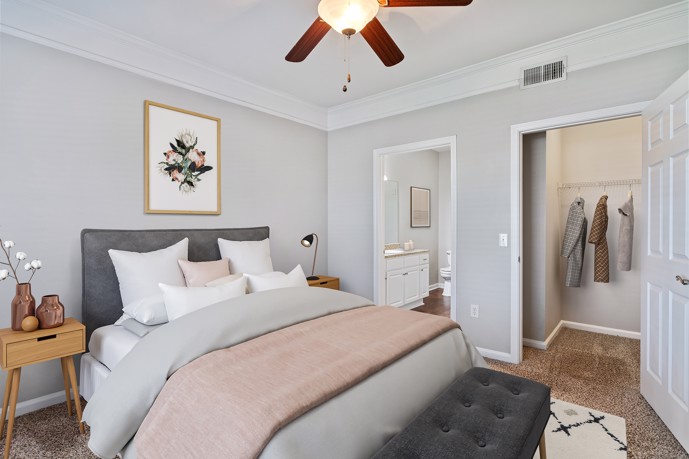Furnished grey Carrington Place apartment bedroom with carpeting and doors to a closet and bathroom