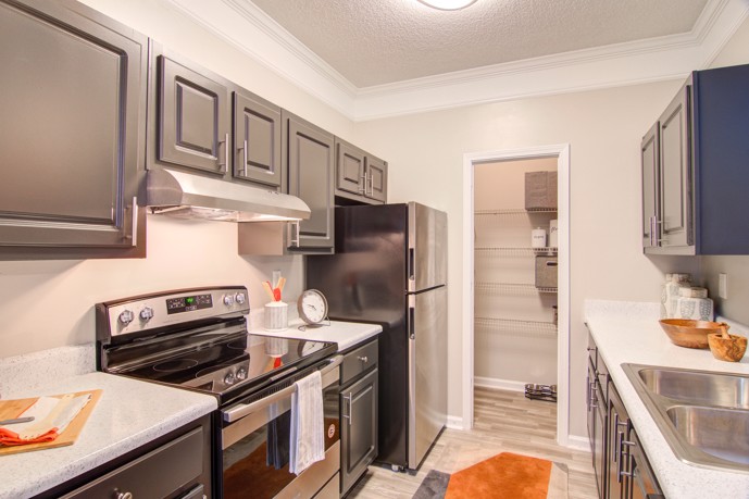 A sleek Waterford Landing apartment galley kitchen with modern grey cabinets, stainless steel appliances, and a convenient pantry closet. 