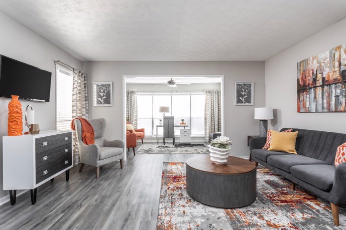 The Pointe at Canyon Ridge apartment boasting an open-floor plan with sleek grey wood-style flooring, featuring a living area transitioning into an office room.