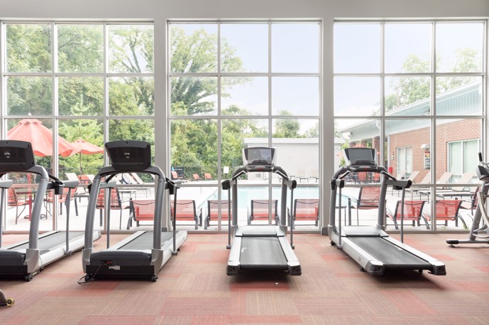 Fitness center with expansive windows overlooking the pool area.