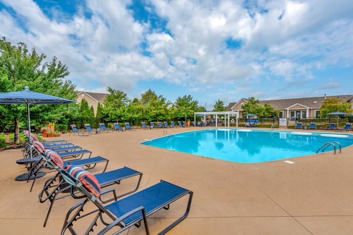 Inviting swimming pool area, complete with a spacious sundeck, comfortable lounge chairs, and shaded umbrellas.