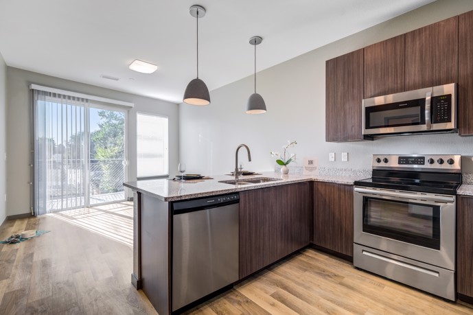 A contemporary kitchen in Patina Flats at the Foundry, featuring modern appliances, sleek cabinetry, and stylish countertops, providing residents with a functional and elegant space for cooking and dining.