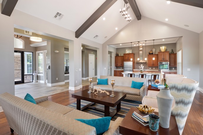 An inviting clubhouse interior adorned with stylish furnishings, a cozy fireplace, and large windows that let in plenty of natural light, creating a warm and welcoming atmosphere for residents to gather and socialize.