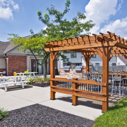 Outdoor wooden gazebo in a common area with both lawn and a gravel plot at Avery Point apartments on a cloudy day in Indianapolis, IN