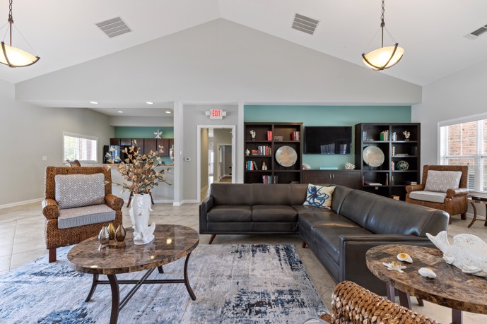 A welcoming lounge area with comfortable seating and a well-equipped kitchen at The Tides of Calabash in Sunset Beach, North Carolina, providing residents with a stylish and convenient space for social gatherings and entertaining.