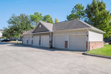 Six-car garage with a paved driveway in front it and trees behind it
