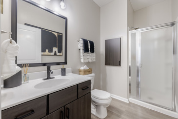 A bathroom with wood-style flooring, a dark vanity, and a shower stall at The Chelsea.