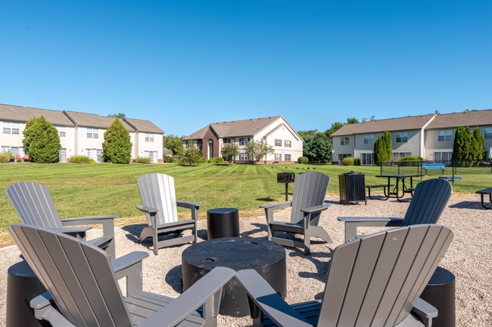Outdoor fireside lounge area with fire pit and chairs surrounding it on a lawn at BriceGrove Park apartments in Canal Winchester, OH