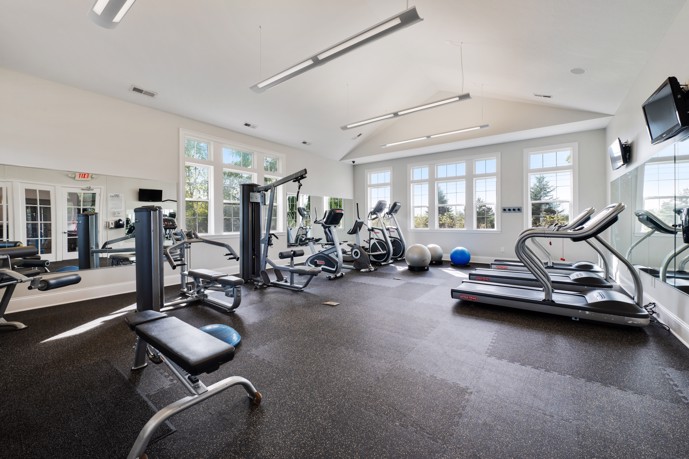Fitness center featuring cardio and weight equipment, mirrors, and expansive windows along two walls.