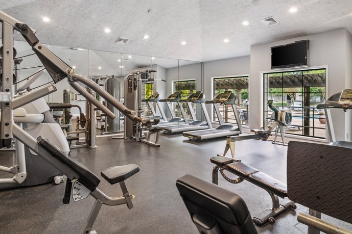 The fitness center at Ridge Crossings with exercise equipment and mirrors for workouts and training sessions.