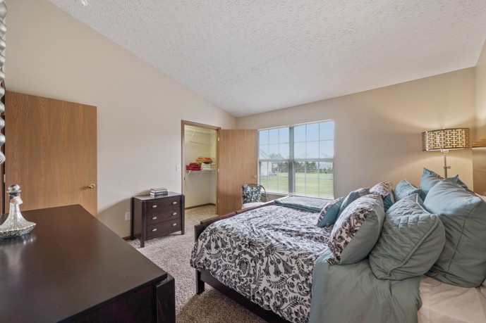A serene bedroom featuring a large window, ample closet space, and convenient access to the hallway.