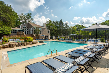 Pool area at The Landings of Brentwood, featuring lounge chairs, umbrellas, and surrounded by lush landscaping, offering a relaxing outdoor retreat.