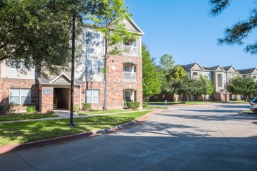 Exterior view of Carrington place apartments with a paved roadway and trees all around the buildings