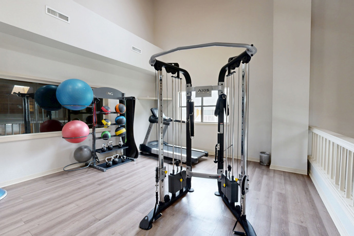 The carpeted fitness center at Windrush apartments in Edmond, OK, featuring a wide range of gym equipment options.