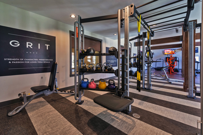 Fitness center featuring weight and cardio equipment, ample windows, mirrors, and a ceiling fan.