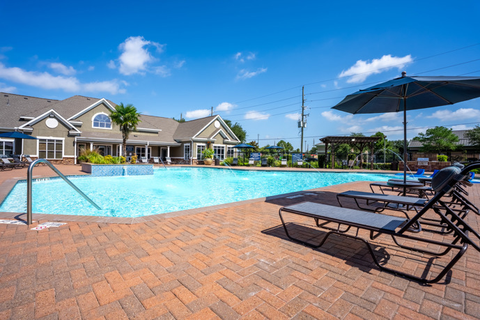 Outdoor swimming pool surrounded by lounge chairs and a sundeck at Waterford Place at Riata Ranch.