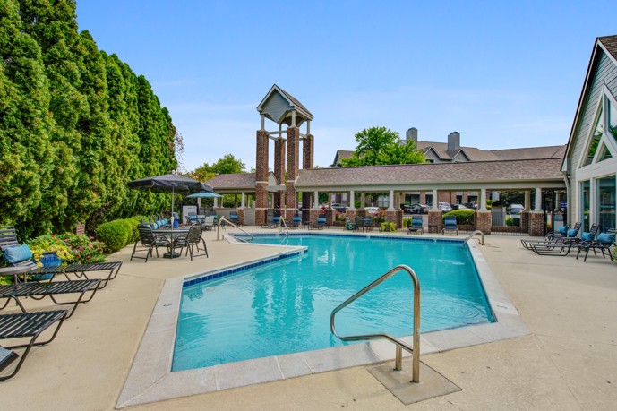A luxurious pool area surrounded by lounge chairs, umbrellas, and lush landscaping, providing residents with a refreshing oasis to relax, swim, and soak up the sun while enjoying the amenities of Prospect Park.